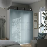 PAX: tall, light blue wardrobe with mirrored doors. Surrounded by furniture, has large size.