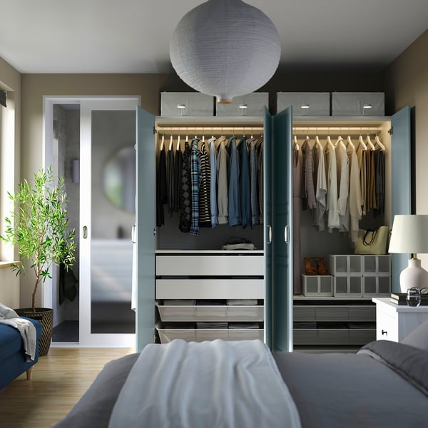 Bedroom with open wardrobe showcasing clothes, drawers, and storage solutions. Led lights illuminate the interior.