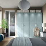 Modern bedroom with light blue wardrobe, pendant light, and plant by bathroom door.