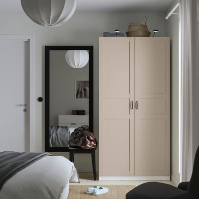Modern bedroom with PAX wardrobe, mirror, table. Corner wardrobe, gray bedding, soft light, minimalist design.