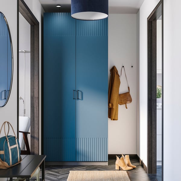Modern entryway with blue cabinet, mirror, rug, and coat/bag.