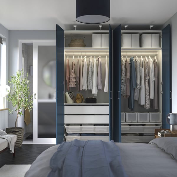 Modern bedroom with open wardrobe, neatly arranged clothes, and grey bedding.