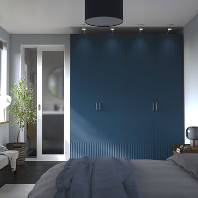 PAX wardrobe with 4 doors next to bathroom glass door. Silver handles, bed with grey comforter, houseplant, and lamp.