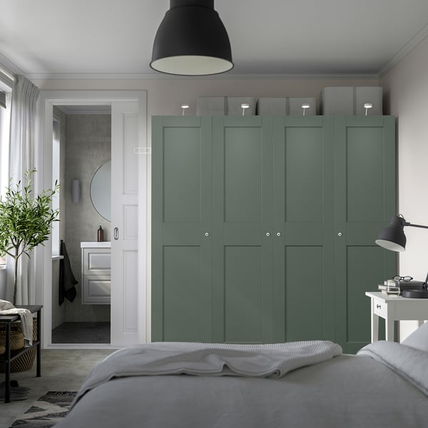 Modern bedroom with large green PAX wardrobe, minimalist design, grey storage, partial bed view, adjacent bathroom with circular mirror.