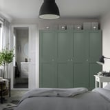 Modern bedroom with large green PAX wardrobe, minimalist design, grey storage, partial bed view, adjacent bathroom with circular mirror.