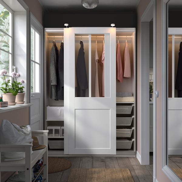 White PAX wardrobe with glass doors, displaying clothes and organized storage.