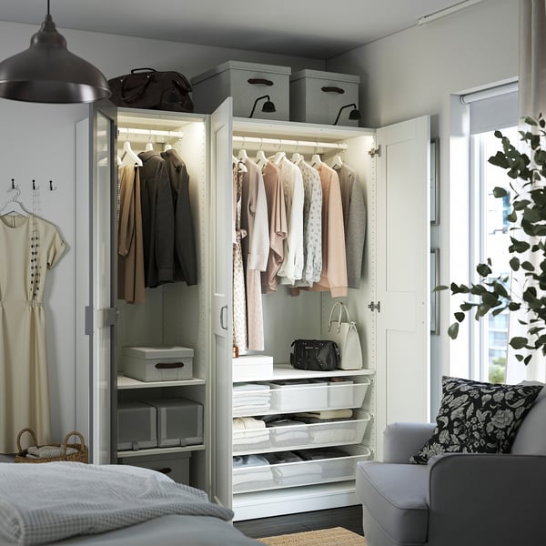 Open wardrobe with mirror doors, clothes hangers, lit shelves, drawers, baskets, and storage boxes for organized bedroom storage.