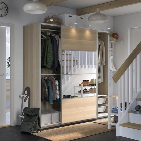 Modern entryway with light wood PAX closet, glass doors, hanging clothes, shelves, and a backpack.