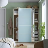 Sliding door wardrobe in light blue reflects bedroom, showcasing organized storage.