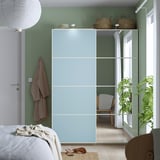 Light blue PAX wardrobe with mirrors, baskets, and towel rail. White bed and plant nearby.