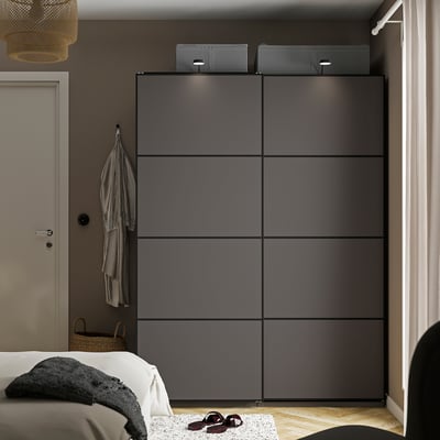 Dark grey PAX wardrobe next to bed, tall with multiple compartments.