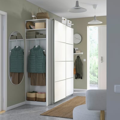 Modern bedroom with white PAX wardrobe, sliding doors, hanging clothes, shelves, and drawers.