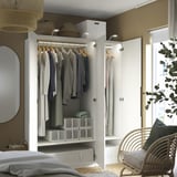 Open white wardrobe displaying clothes on hangers, boxes, and folded garments, featuring hanging rods and shelves.