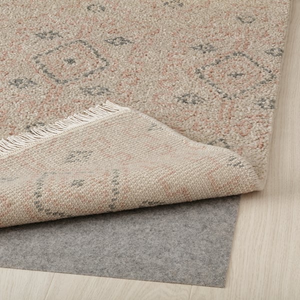 Rug with fringes, light diamonds, and non-slip pad underneath.