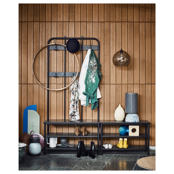 Modern entryway with black metal shoe rack and coat hooks, wooden wall paneling, and various decorative items.