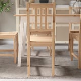 Wooden chair with vertical slats, designed to fit under table, offering space-saving functionality.
