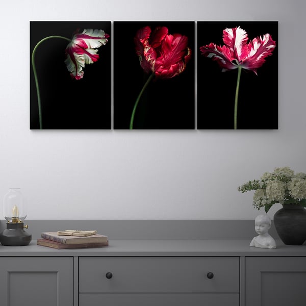 Three colorful PJÄTTERYD floral art pieces and decorative items on a gray console.