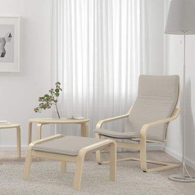 POÄNG armchair in beige with cushions and footstool. High-back birch wood design, light beige fabrics, window view.