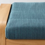 Close-up of teal cushion on wooden surface; soft, textured fabric.