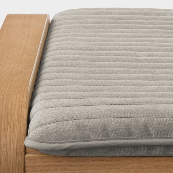Close-up of a comfortable, modern chair with a wooden frame and a textured gray cushion.