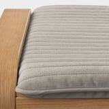 Close-up of a comfortable, modern chair with a wooden frame and a textured gray cushion.