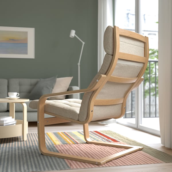 Modern living room with a brown POÄNG armchair featuring a high back for neck support, positioned near a window on a multicolored rug.