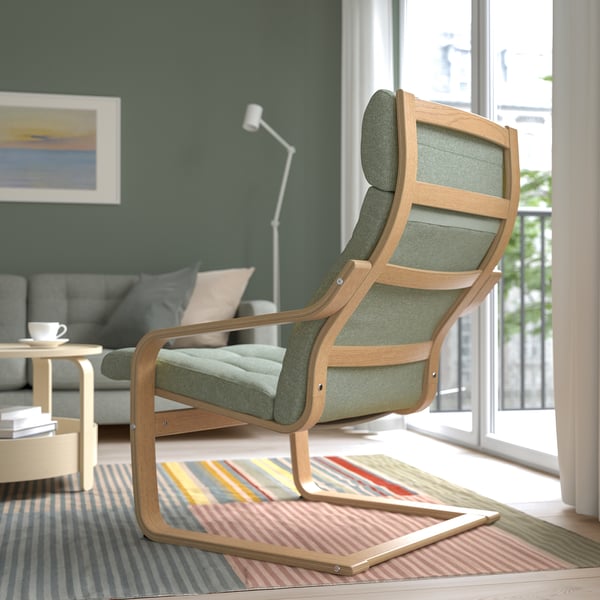 A modern living room with a wooden and green cushioned rocking chair near a window, offering neck support and relaxation.