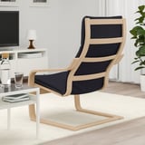 Black cushioned armchair with wooden frame, accompanied by a white side table holding books and a water bottle.