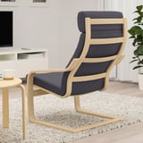 Dark gray POÄNG armchair with curved wooden frame, cushioned seat, and high back for neck support in a cozy living room.