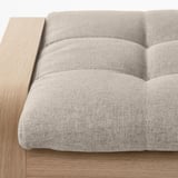 Close-up of a light gray cushioned seat of a wooden furniture. Soft, modern design with visible stitching.
