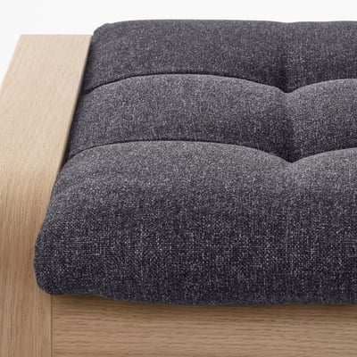 Close-up of modern sofa with dark cushions and oak frame, showcasing high-quality materials.