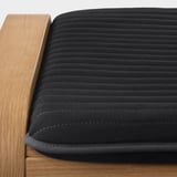 Close-up of dark cushion on wooden furniture, showcasing quilted texture and sturdy craftsmanship.