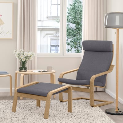 Modern living room with gray POÄNG recliner, footstool, and side table. White flowers in a vase.