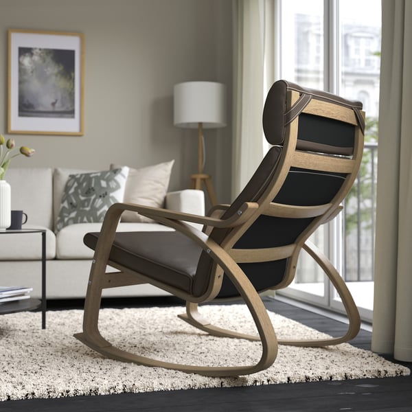 Modern rocking chair with high back and cushioned seat, perfect for relaxing by a window with natural light and views.