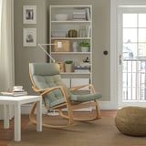 Cozy living room with green rocking chair, side table, books & natural light.