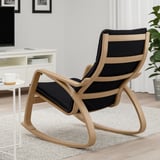 Modern rocking chair in a living room with wooden frame and black cushions. The chair is designed for comfort and relaxation.
