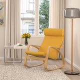 Bright yellow POÄNG rocking chair near large window with side table, lamp, and flowers.