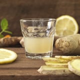 Glass filled with yellow drink, surrounded by ginger, lemon slices, highlighting its classic design suitable for various occasions and healthy drinks.