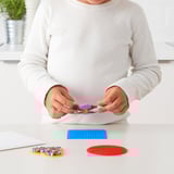 A child assembles colorful beads on a blue base. Depicts the PYSSLA bead set, promoting creativity and motor skill development.