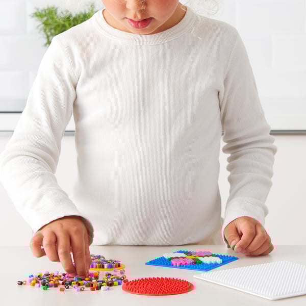 Child crafting beads on pegboard, improving motor skills.