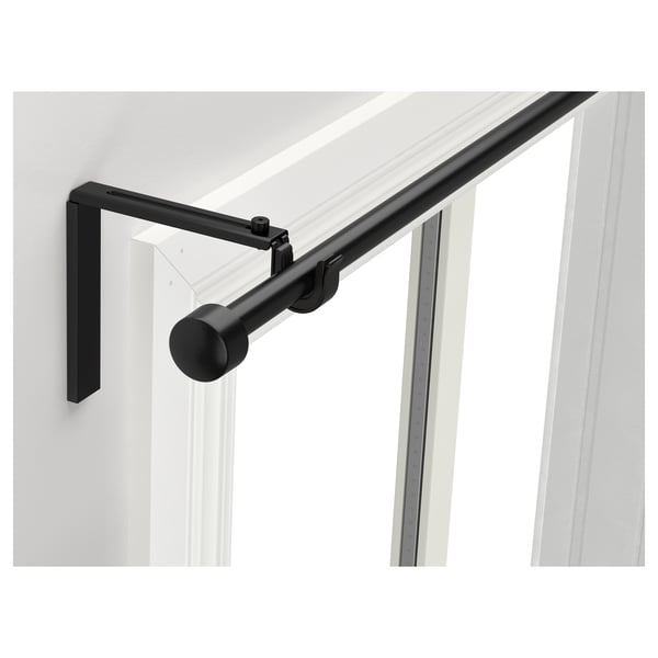 Black RÄCKA curtain rod, adjustable, modern design, mounted on white wall near window.