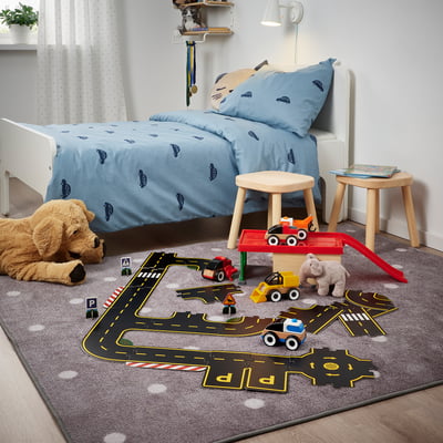 Childs play area with car bedding, toys, mat, stool. Alternative: kids car-themed play area with toys, mat, stool.