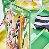 Colorful towels hang on green rack, perfect for drying dishes. Bright patterns add kitchen charm.