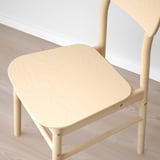 Light wooden chair with smooth, rounded seat and backrest, displaying natural grain texture, set on a wooden floor.