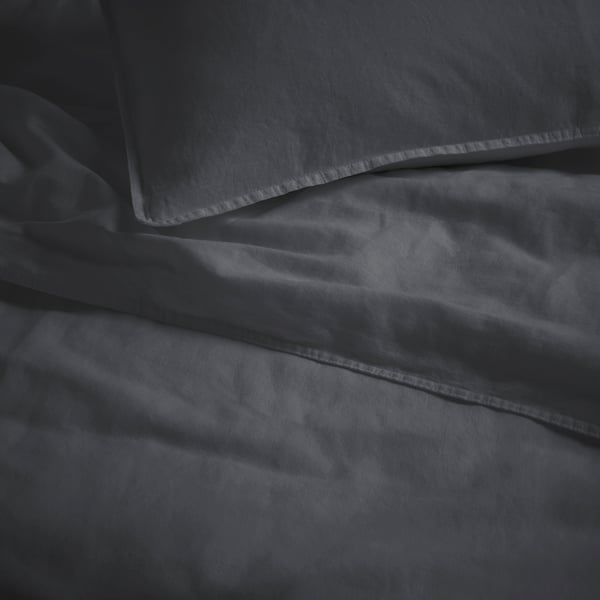 Soft, dark gray bed linen, neatly made, showcasing fine stitching and smooth texture.