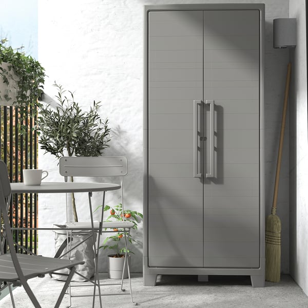 Gray RUNMARÖ cabinet outdoors with plastic dining set. Sleek, rectangular with two doors, ideal for storage.