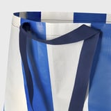 Blue and white shopping bag with strong handles shown in close-up, highlighting fabric quality.