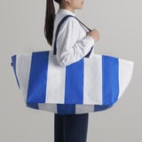Person holding blue & white striped bag. Folds flat, easy to clean.