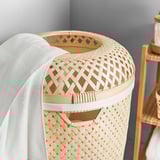 Wicker laundry basket with white liner, natural bamboo, circular design.