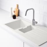 Clean, modern kitchen sink with a sloping drainboard on the right, silver faucet, and backsplash.